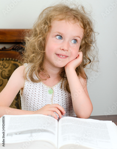 Photo: Cute little smiling girl reading a book Cute little smiling girl reading a book