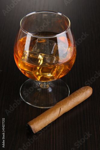 Photo: Brandy glass with ice on wooden background Brandy glass with ice on wooden background