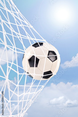 Photo: Soccer ball in a net against cloudy sky Soccer ball in a net against cloudy sky