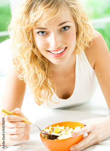 Photo: Cheerful woman eating cereal muslin Cheerful woman eating cereal muslin
