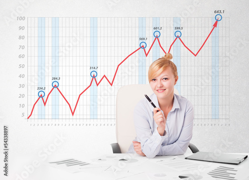 Photo: Young businesswoman calculating stock market with rising graph i Young businesswoman calculating stock market with rising graph i