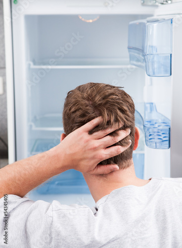Photo: Thoughtful man looking in empty refrigerator Thoughtful man looking in empty refrigerator