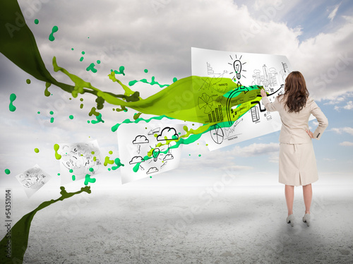 Photo: Creative businesswoman drawing on a paper next to paint splash Creative businesswoman drawing on a paper next to paint splash
