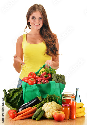 Photo: Young woman with variety of grocery products in shopping bag Young woman with variety of grocery products in shopping bag
