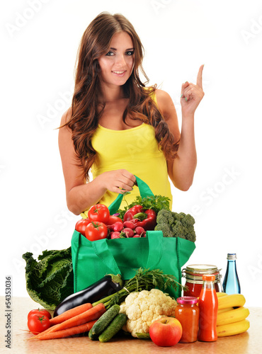 Photo: Young woman with variety of grocery products in shopping bag Young woman with variety of grocery products in shopping bag