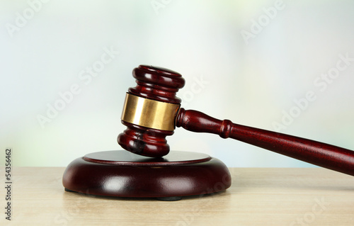 Photo: Judges gavel on wooden table on light background Judges gavel on wooden table on light background