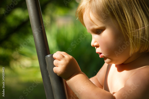 Photo: Young child exploring and touching a metal bar in the garden Young child exploring and touching a metal bar in the garden