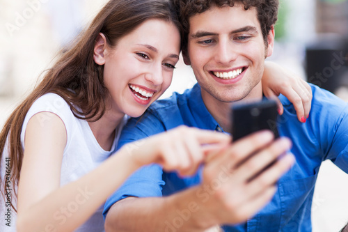 Photo: Young couple looking at mobile phone Young couple looking at mobile phone