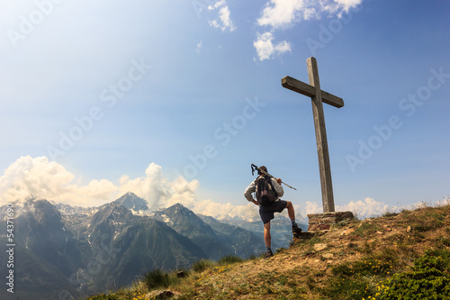 Photo: Ragazzo osserva panorama in cima alla vetta con croce Ragazzo osserva panorama in cima alla vetta con croce