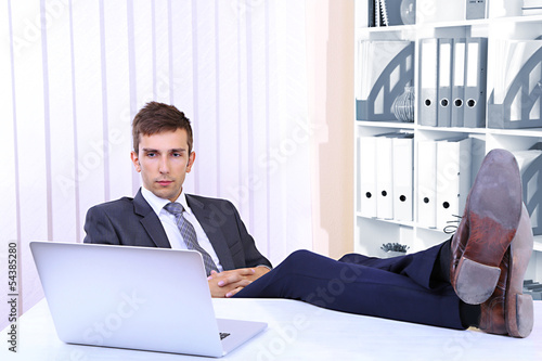 Photo: Businessman resting at his office with his shoes on table Businessman resting at his office with his shoes on table