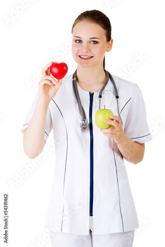 Photo: Smiling woman doctor with a green apple and red heart. Smiling woman doctor with a green apple and red heart.