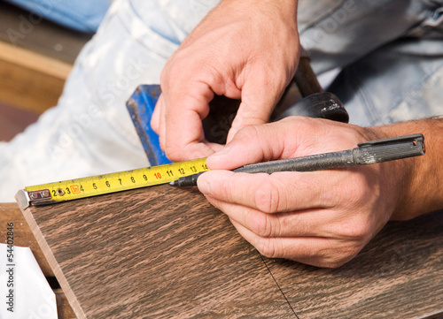 Photo: Man measuring a tile piece with a marker Man measuring a tile piece with a marker