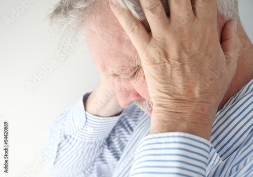 Photo: stressed older man holds his head in both hands stressed older man holds his head in both hands