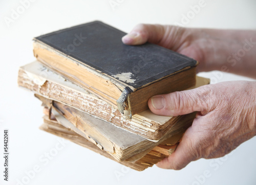 Photo: man holds several old, damaged books man holds several old, damaged books