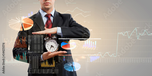 Photo: Business man holding alarmclock Business man holding alarmclock
