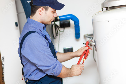 Photo: Plumber repairing a hot-water heater Plumber repairing a hot-water heater