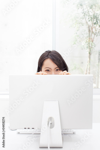 Photo: モニターの陰から覗く女性 モニターの陰から覗く女性
