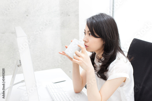 Photo: デスクでコーヒーを飲む女性 デスクでコーヒーを飲む女性
