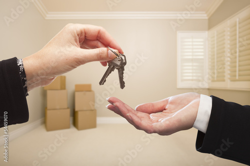 Photo: Woman Handing Over the House Keys Inside Empty Tan Room Woman Handing Over the House Keys Inside Empty Tan Room