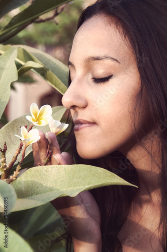 Photo: Portait of sensual young woman taking a smell at a blossom Portait of sensual young woman taking a smell at a blossom