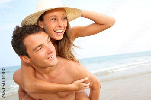 Photo: Man giving piggyback ride to girlfriend by the ocean Man giving piggyback ride to girlfriend by the ocean