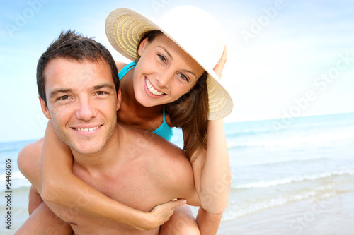 Photo: Man giving piggyback ride to girlfriend by the ocean Man giving piggyback ride to girlfriend by the ocean