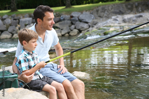 Photo: Father teaching son how to fish in river Father teaching son how to fish in river