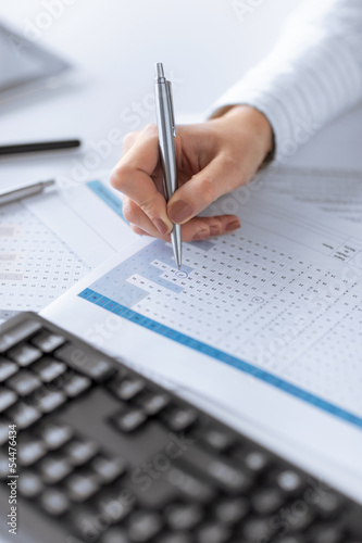 Photo: woman hand writing on paper with numbers woman hand writing on paper with numbers
