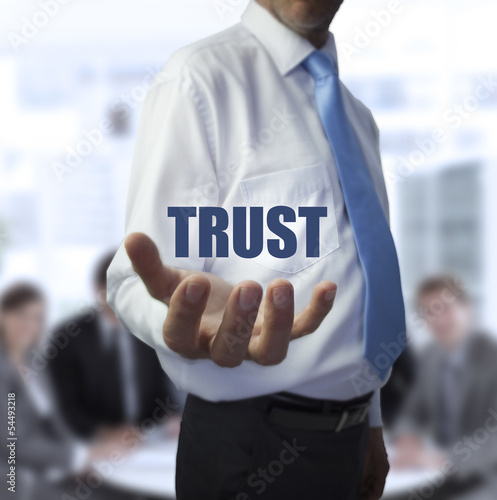 Photo: Elegant businessman holding the word trust Elegant businessman holding the word trust