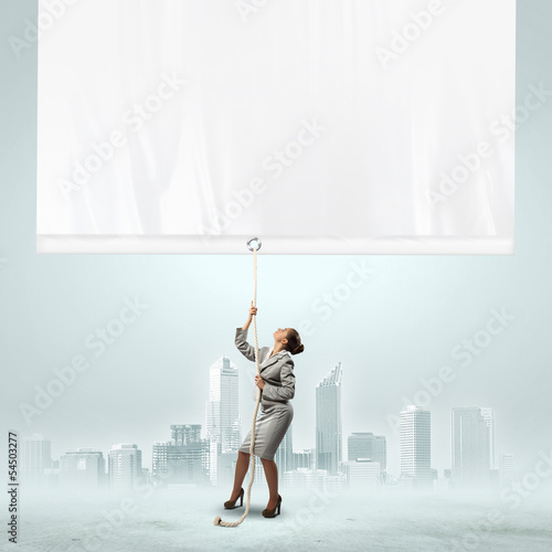 Photo: Businesswoman pulling blank banner Businesswoman pulling blank banner