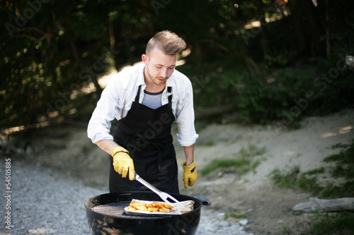 Photo: junger Mann beim Grillen junger Mann beim Grillen