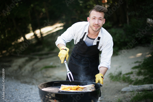 Photo: junger Mann beim Grillen junger Mann beim Grillen