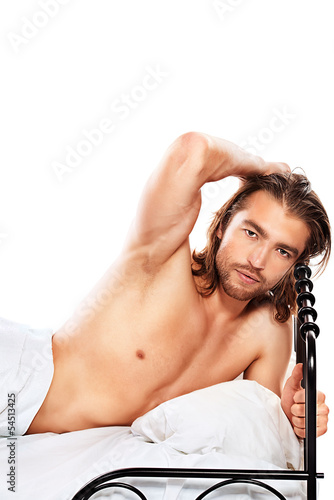 Photo: Handsome nude man lying in a bed. Isolated over white. Handsome nude man lying in a bed. Isolated over white.