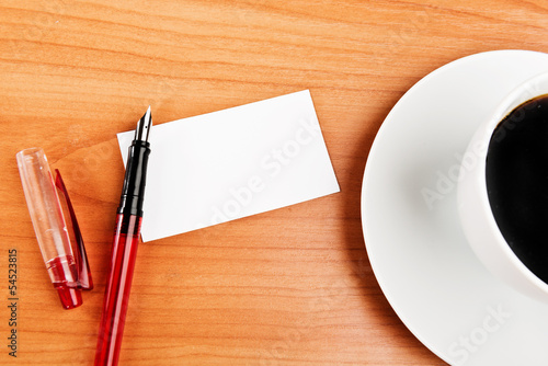 Photo: coffee cup, piece of paper and pen on the wooden table coffee cup, piece of paper and pen on the wooden table