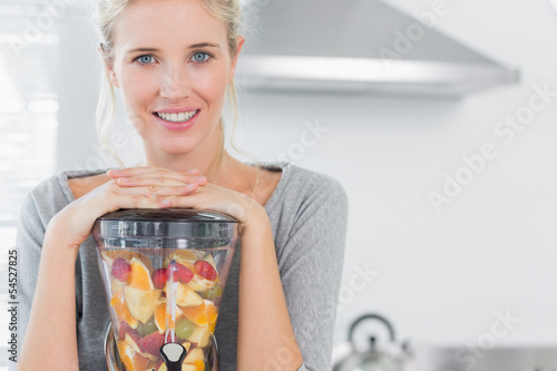 Photo: Blonde woman leaning on her juicer and smiling at camera Blonde woman leaning on her juicer and smiling at camera