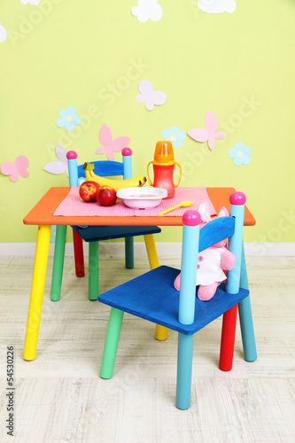 Photo: Tasty baby fruit puree and baby bottle on table in room Tasty baby fruit puree and baby bottle on table in room