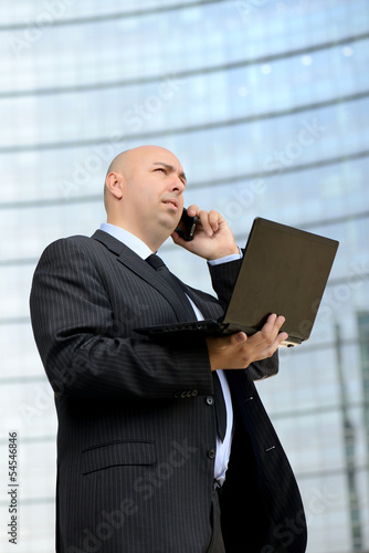 Photo: Uomo d'affari al telefono con computer portatile Uomo d'affari al telefono con computer portatile