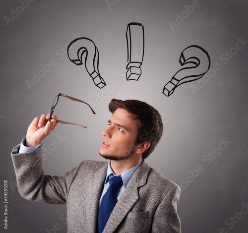 Photo: Young man thinking with question marks overhead Young man thinking with question marks overhead