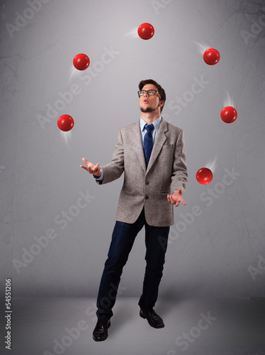 Photo: young man standing and juggling with red balls young man standing and juggling with red balls