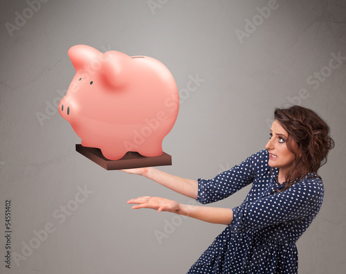 Photo: Young girl holding a huge savings piggy bank Young girl holding a huge savings piggy bank