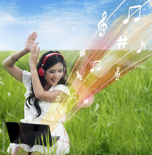 Photo: Excited female download music from laptop - outdoor Excited female download music from laptop - outdoor