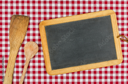 Photo: Leere Schiefertafel mit Kochlöffel auf einem Tischtuch Leere Schiefertafel mit Kochlöffel auf einem Tischtuch