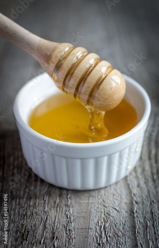 Photo: Honey bowl with dipper and flowing honey Honey bowl with dipper and flowing honey