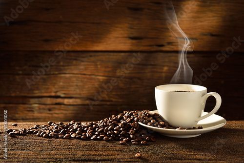 Kubek zaparzonej kawy, wsród ziaren kawy na tle z desek