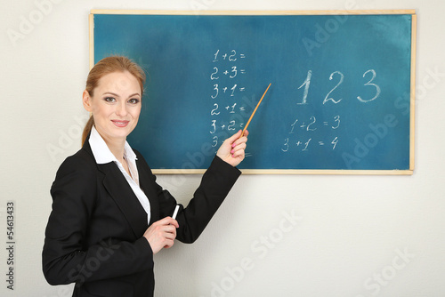 Photo: Portrait of teacher woman near chalkboard in classroom Portrait of teacher woman near chalkboard in classroom