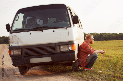 Photo: Driver sits next to his car Driver sits next to his car