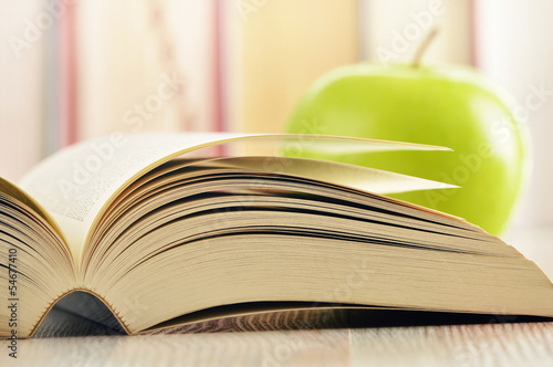 Photo: Composition with green apple and books on the table Composition with green apple and books on the table