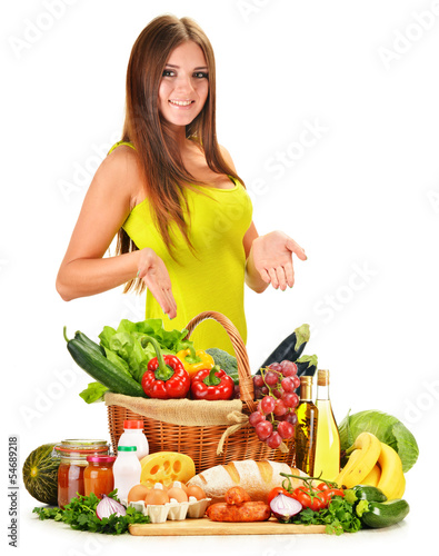 Photo: Young woman with assorted grocery products isolated on white Young woman with assorted grocery products isolated on white