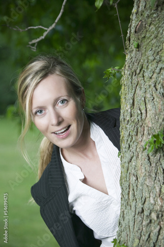 Photo: Junge lachende blonde Frau hinter einem Baum Junge lachende blonde Frau hinter einem Baum
