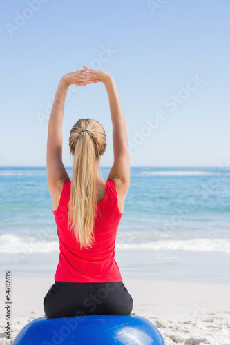 Photo: Fit blonde sitting on exercise ball looking at waves Fit blonde sitting on exercise ball looking at waves
